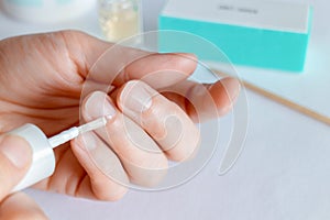 Woman doing manicure, applying oil on cuticles photo