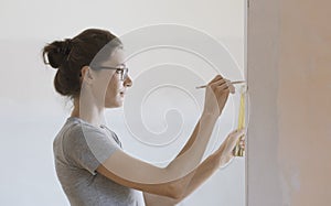 Woman doing a home renovation and measuring walls with a ruler