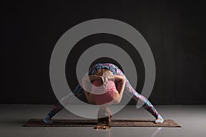 Woman doing Prasarita Padottanasana yoga pose. Studio shot photo