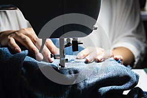 Woman doing jeans patchwork using sewing machine