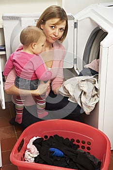 Woman Doing Laundry And Holding Daughter