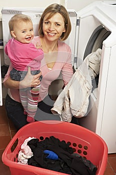 Woman Doing Laundry And Holding Daughter