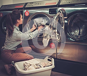 Woman doing laundry at laundromat shop.