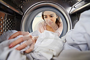 Woman Doing Laundry Reaching Inside Washing Machine