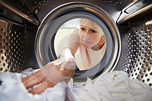 Woman Doing Laundry Reaching Inside Washing Machine