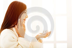 woman doing makeup in front of bathroom mirror