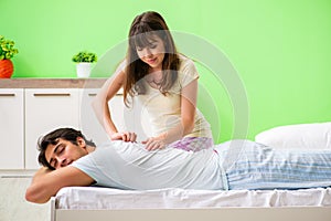 The woman doing massage to her husband in bedroom