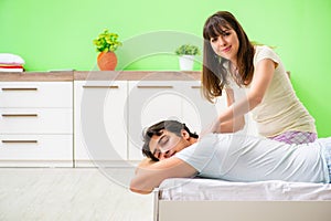 The woman doing massage to her husband in bedroom