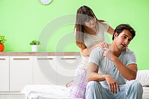 The woman doing massage to her husband in bedroom