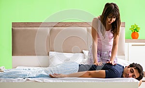 Woman doing massage to her husband in bedroom