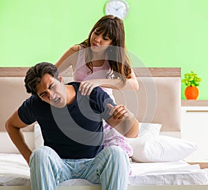 Woman doing massage to her husband in bedroom