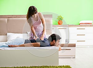 Woman doing massage to her husband in bedroom