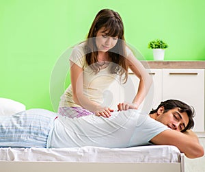 Woman doing massage to her husband in bedroom