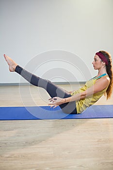 Woman doing navasana yoga pose on exercise mat