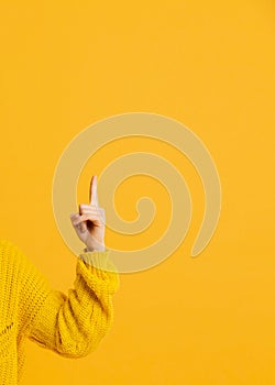 Woman doing one finger or pointing hand on a yellow background