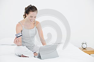 Woman doing online shopping in bed