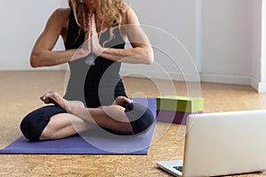 Woman doing online yoga class sitting in padmasana
