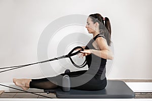A woman doing pilates exercises on a reformed bed.
