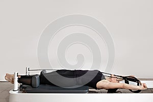 A woman doing pilates exercises on a reformed bed.