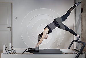 A woman doing pilates exercises on a reformed bed.