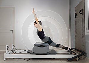 A woman doing pilates exercises on a reformed bed.
