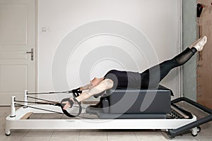 A woman doing pilates exercises on a reformed bed.