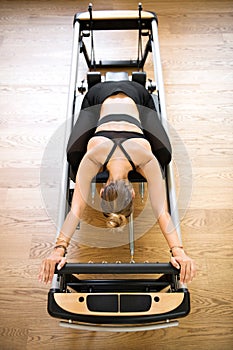 Woman doing pilates stretch on reformer bed