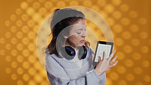 Woman doing promotion for reading tablet, showing features, studio background