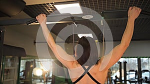 A woman is doing pull ups on a bar in a gym