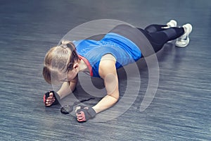 Woman doing push-up exercise. Strong female doing crossfit workout. blonde stands on her elbows and looks at the stopwatch on the