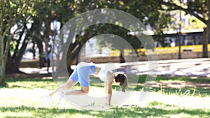 A woman is doing a push up on the grass