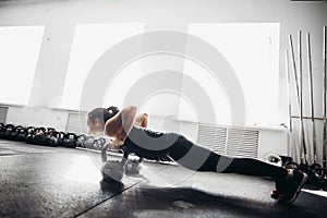 Woman doing push-ups exercises on kettlebells. Cross fit training