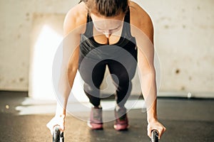 Woman doing push-ups exercises on kettlebells. Cross fit training