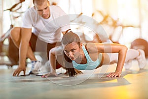 Woman doing push ups under supervision of a trainer