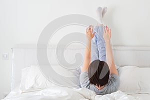 Woman doing some exercise lying in bed with legs high up