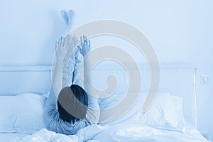 Woman doing some exercise lying in bed with legs high up