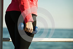 Woman doing sports outdoors with dumbbells