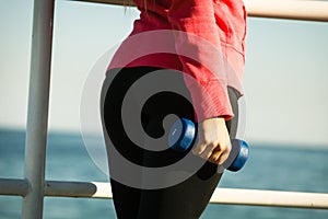 Woman doing sports outdoors with dumbbells