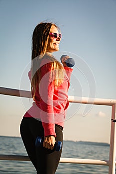Woman doing sports outdoors with dumbbells