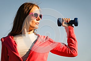 Woman doing sports outdoors with dumbbells