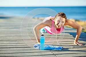 Woman doing sports outdoors on a wooden path at the sea