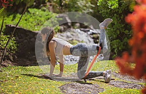 Woman doing sports outdoors. Young girl performing bodyweight fitness training on the nature. Beautiful female doing