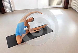 Woman doing stretching in revolved head to knee pose, opening her chest towards the ceiling, warm up