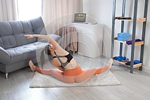 Woman is doing stretching side tilts exercises sitting on carpet at home.