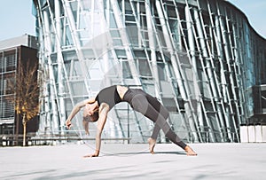 Woman doing stretching yoga exercises outside in the city