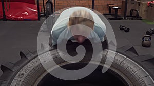 Woman doing tire flips power lifting workout at gym