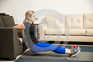 Woman doing tricep dips on a couch at home