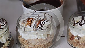 A woman is doing trifles. Garnishes trifles in jars with liquid caramel. Close-up