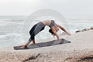 Woman doing Wild Thing yoga pose outdoors. Female practicing Camatkarasana pose at evening