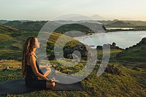 Woman doing yoga alone at sunrise with mountain view. Harmony with nature